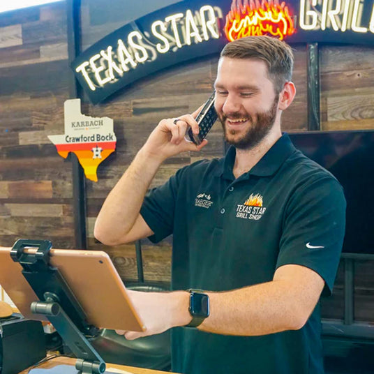 Salesperson from Texas Star Grill Shop assisting a customer over the phone with a tablet