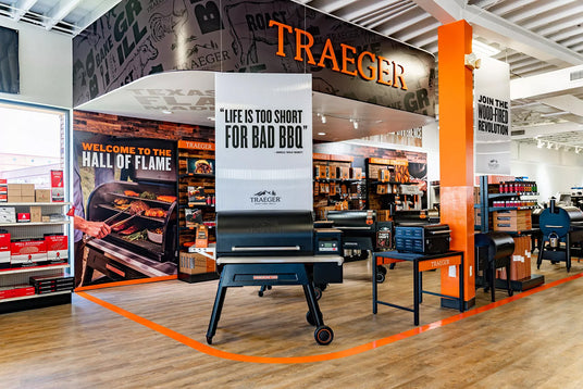 Traeger grill showroom at Texas Star Grill Shop featuring wood pellet grills, accessories, and branding displays with slogans like ‘Hall of Flame’ and ‘Life is too short for bad BBQ.’