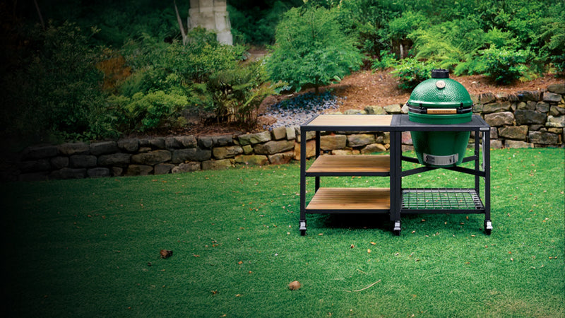 Green Big Green Egg barbecue grill on a grassy area with a natural background