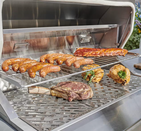 Grilling food on Coyote pellet grill with meats and vegetables on sear grates.