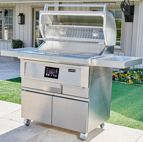 Coyote 36-Inch pellet grill on freestanding cart in outdoor setting.