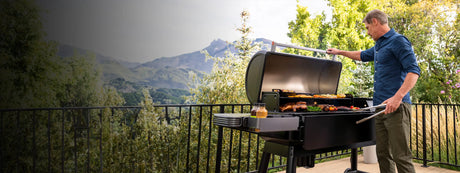 man cooking on a traeger ironwood xl with a nice view