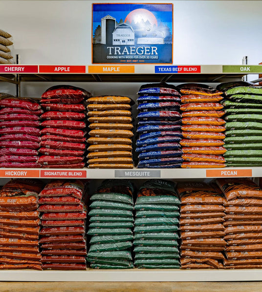 Shelves stacked with Traeger wood pellets in various flavors including Cherry, Apple, Maple, Texas Beef Blend, Oak, Hickory, Signature Blend, Mesquite, and Pecan at Texas Star Grill Shop.