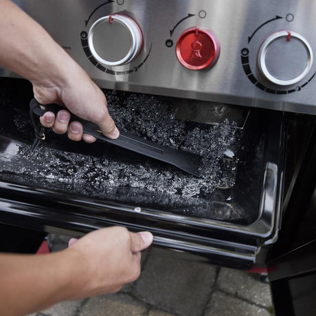 Person removing the grease tray for cleaning from Weber Genesis SP-S-325 grill