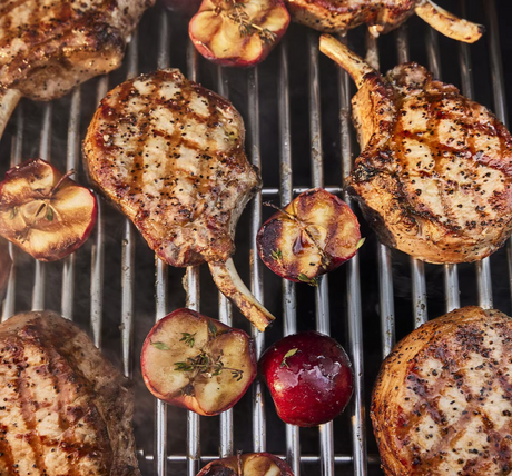 Pork chops and vegetables grilling over flames on Weber Genesis SP-S-325