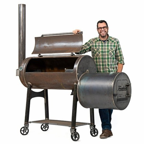 aaron franklin standing next to his franklin barbecue offset smoker pit, made of high quality rolled american steel with an 82-inch cook chamber, available at texas star grill shop